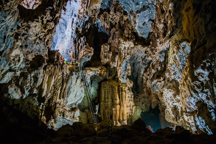 Descend a 10m high ladder while wearing safety harnesses in Hang Ton Cave